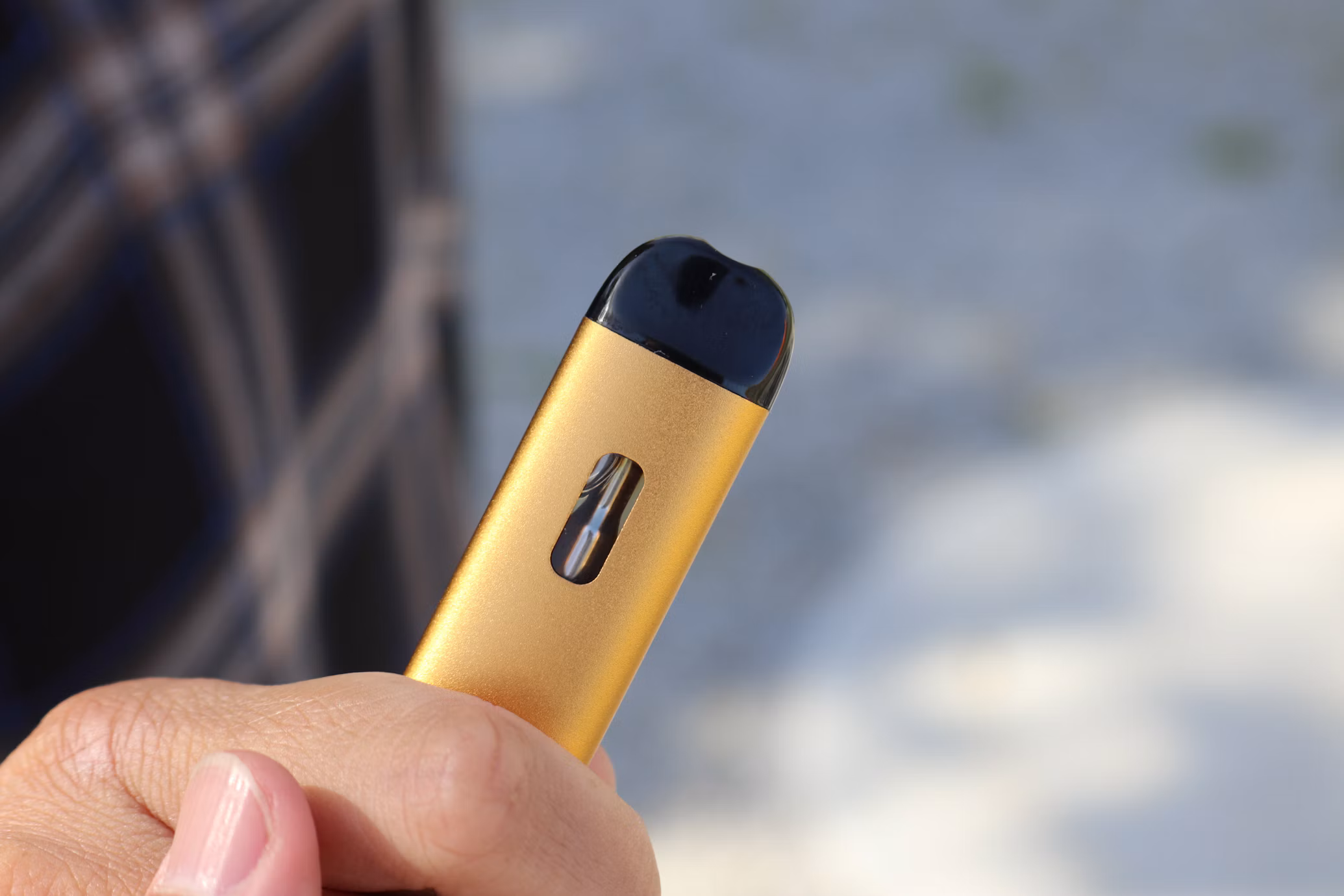 Hand holding a gold pod vape